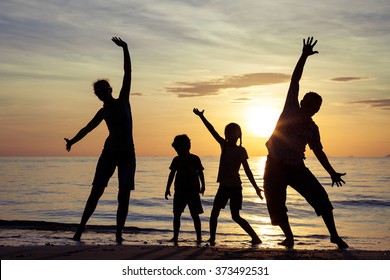 Silhouette Of Happy Family Who Playing On The Beach At The Sunset Time. Concept Of Friendly Family.