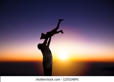 The silhouette of happy father and little girl with sunrise background