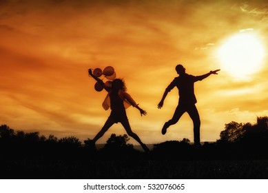 Silhouette of happy lovers jumping against sunset. light and shadow