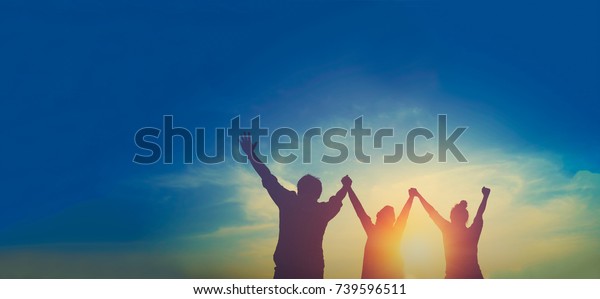 Silhouette of happy\
teamwork hold hands up as a business successful, business victory,\
achieve business\
goal