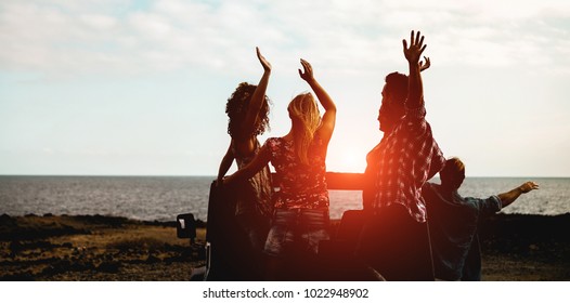 Silhouette of happy tourists friends doing excursion next the beach on convertible 4x4 car - Young people having fun traveling together - Friendship and vacation concept - Focus on center guys - Powered by Shutterstock