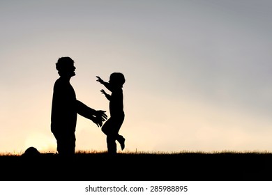 Silhouette of a happy young child smiling as he runs to greet his father with a hug at sunset on a summer day.