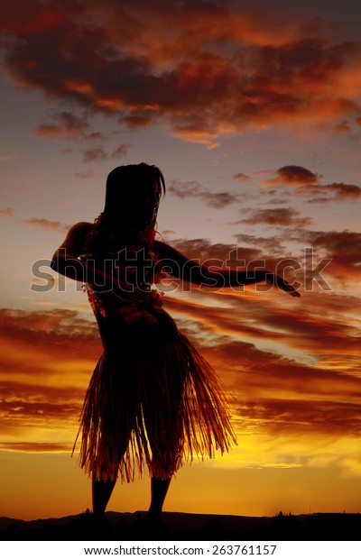 a\
silhouette of a Hawaiian woman dancing in the\
outdoors.