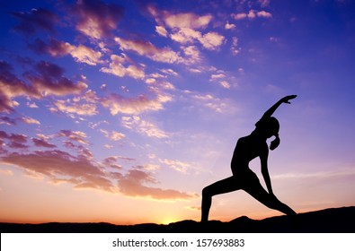Silhouette of healthy woman doing yoga meditation during sunrise with natural sunlight outdoor.