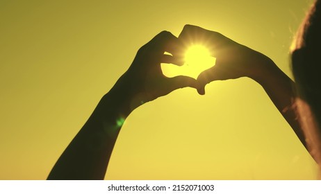 Silhouette Of The Heart In The Rays Of The Sun. Make Heart Symbol With Hands. Valentine. Love Sign. Freedom Of Travel. Happiness Of A Woman's Dream. Heart Against The Sky. Declaration Love To Person