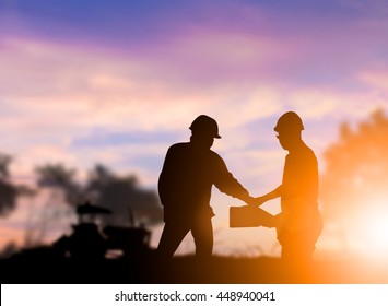 Silhouette Heavy industry engineer construction industry stands shake hands with the team contract business in large farms over blurred pastel background sunset.  concept.