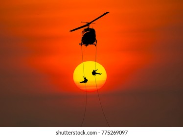 Silhouette Of Helicopter, Soldiers Rescue Helicopter Operations On Sunset Sky Background.