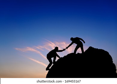 Silhouette of helping hand between two climber 