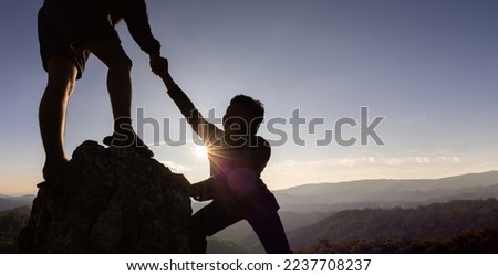 Silhouette of helping hand between two climber. couple hiking help each other silhouette in mountains with sunlight. The men helping pull people up from high cliffs