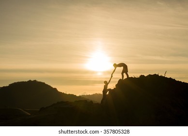 Silhouette Of Helping Hand On Mountains In Sunset Background.