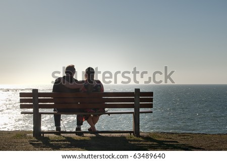Silhouette of a heterosexual couple enjoying the afternoon on a calm and peaceful relaxing in front of the ocean view. Copyspace above with room for text.