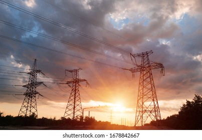 A silhouette of high voltage power lines against a colorful sky at sunrise or sunset.