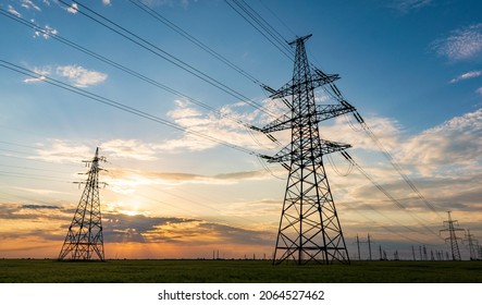 silhouette of high voltage power lines against a colorful sky at sunrise or sunset. - Shutterstock ID 2064527462