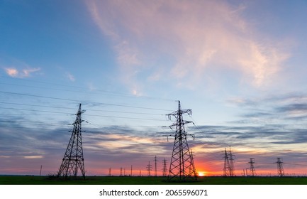 Silhouette Of High Voltage Power Lines Against A Colorful Sky At Sunrise Or Sunset.