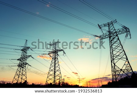 silhouette of high voltage power lines against a colorful sky at sunrise or sunset.