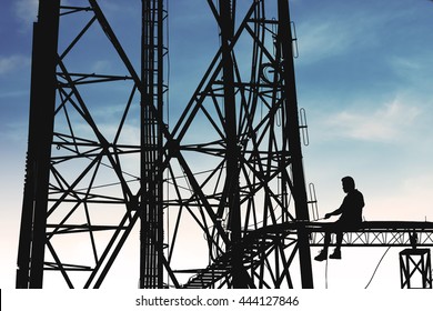 Silhouette, high voltage tower, telecommunication tower, TV antennas with worker repairing, maintenance on blue sky with copy space