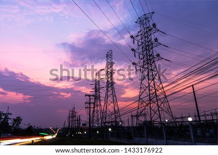 Silhouette of high voltage tower and wires In the power supply station There is a twilight background and have many car traffic.