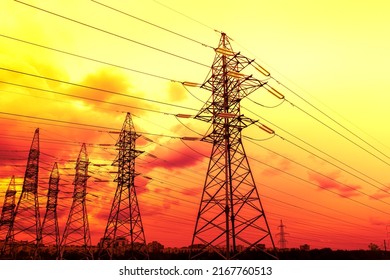 Silhouette of high-voltage electrical towers on a sunset background. Industrial landscape.
