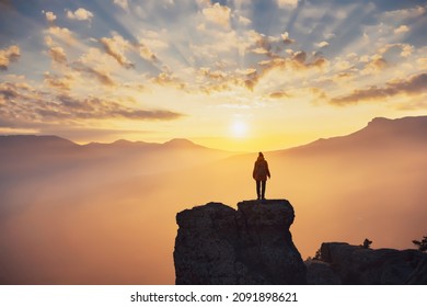 Silhouette of hiker girl enjoying sunlight in mountains at sunset. Concept of travel or hiking