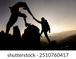 Silhouette of hiker helping each other hike up a mountain at sunset. People helping and, team work concept.