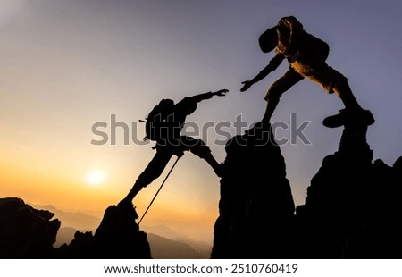 Silhouette of hiker helping each other hike up a mountain at sunset. People helping and, team work concept.