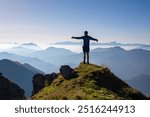 Silhouette of hiker man in alpine landscape of Gailtal Alps, Carinthia, Austria. Panoramic view of majestic hazy mountain ridges of Julian Alps, Karawanks, Carnic Alps. Peaceful tranquil atmosphere