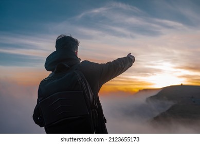 Silhouette of a hiker man hiking on the top mountain at sunset.	