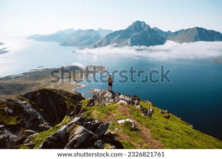 Silhouette of a hiker woman stand on top of mountain hike summit overlooking epic Lofoten Archipelago landscape. Inspiring and amazing idea of adventure. Roadtrip in Norway Stock photo © 