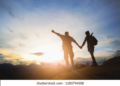 Silhouette of hikers standing on top of hill and enjoying sunrise over the valley - Shutterstock ID 1183794508
