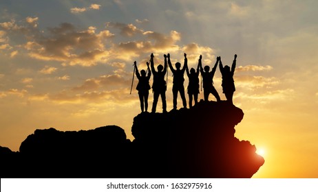 silhouette of the hiking male and female hikers climbing up mountain. they are success full at top the mountain.team work concept.