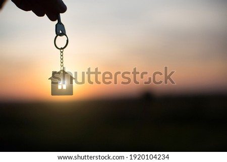 Silhouette of a house figure with a key,  keychain on the background of the sunset. They dream of a house, building, moving to a new house, mortgages, renting and buying real estate. Copy 