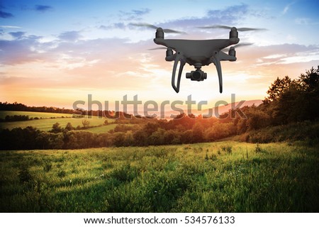 Silhouette of hovering drone taking pictures of nature at sunset