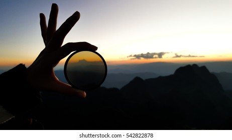 Silhouette of human hand scale traveler hold camera filter glass through the scenic landscape view on evening sunset mountain ridge. - Shutterstock ID 542822878