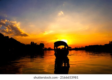 Silhouette image of a boat with beautiful sunset at a serene lake