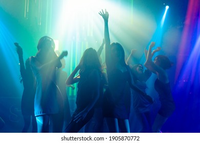 Silhouette image of people dance in disco night club to music from DJ on stage . New year night party and nightlife concept . - Shutterstock ID 1905870772