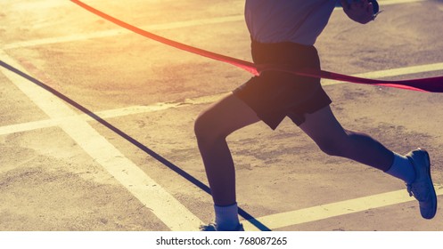 silhouette image of ribbon at finish line with kids winner crossing it.(focus on ribbon)) - Shutterstock ID 768087265