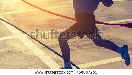 silhouette image of ribbon at finish line with kids winner crossing it.(focus on ribbon))