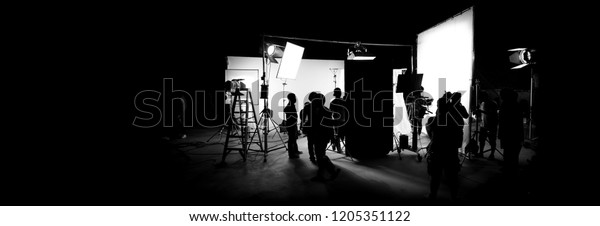 Silhouette\
images of video production behind the scenes or b-roll or making of\
TV commercial movie that film crew team lightman and cameraman\
working together with director in big studio\
