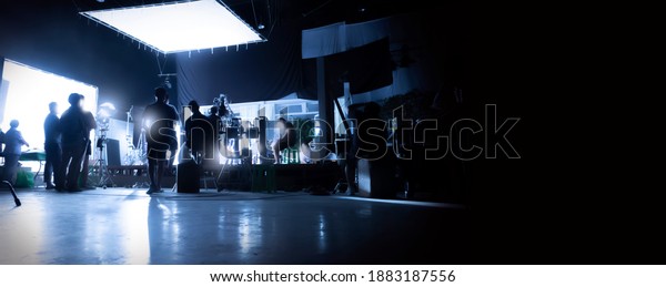 Silhouette images of video production behind the\
scenes or b-roll or making of TV commercial movies that film crew\
team lightman and videos cameraman working together with movie\
director in studio.