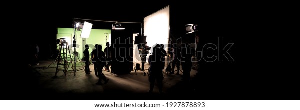 Silhouette images of video production behind the\
scenes. making of TV commercial movie that film crew team lightman\
and cameraman working together with film director in studio. film\
production concept