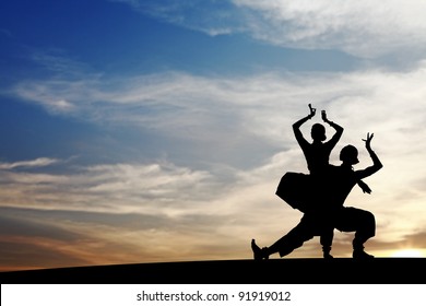 Silhouette Of Indian Cultural Duet Dancers Posing On A Hill Against A Surreal Dramatic Sunset Sky.