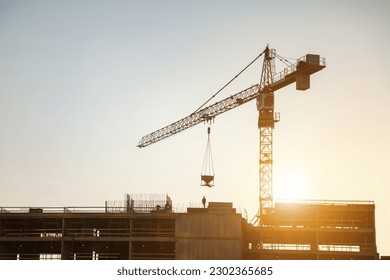 Silhouette of industry crane on construction site at sunset. Industrial crane on creation site house building, aerial view. Construction and renovation of buildings concept. Copy ad text space, banner - Powered by Shutterstock