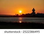 Silhouette of Isla Cristina lighthouse in orange yellow sunset light, Costa de la Luz, Andalusia, Spain