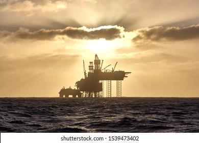 Silhouette Of A Jack Up Drilling Rig In The North Sea At Sunset. North Sea Offshore Platform For Oil And Gas.