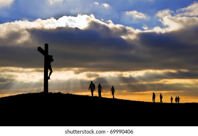 Silhouette of Jesus Christ crucifixion on cross on Good Friday Easter with people walking up hill towards Jesus