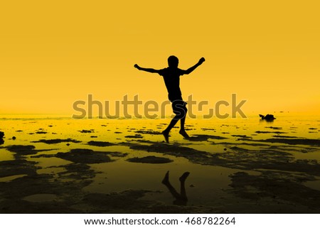 Silhouette of jumping group kid, people stand on beach during sunset with warm tone