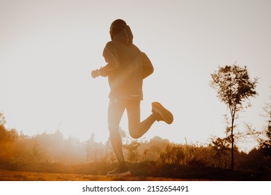 Silhouette Of A Kenyan Runner Running Along A Red Dirt Road Near The City Of Iten In Kenya. Athletic Sports Photo For Long Track And Marathon Runners