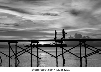 silhouette kid run with happy on the wooden jetty during sunset at Mantanani Island, Kota Belud, Sabah, Malaysia in Black and white - Powered by Shutterstock