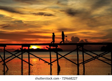 silhouette kid run with happy on the wooden jetty during sunset at Mantanani Island, Kota Belud, Sabah, Malaysia - Powered by Shutterstock