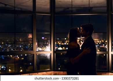 Silhouette kissing couple on panoramic window background with nigth luminous city view. Love in the night city concept, copy space - Powered by Shutterstock